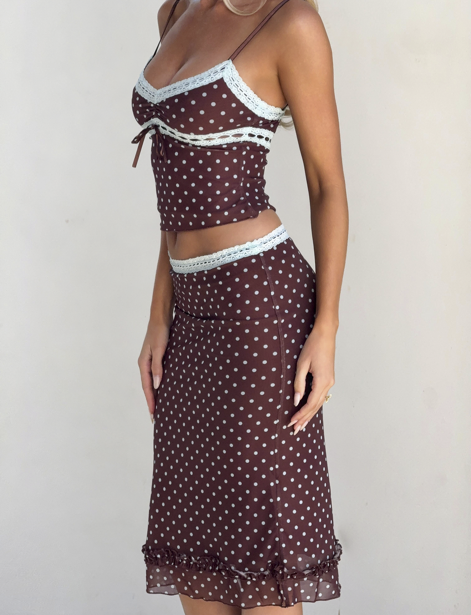 A woman models the TIGERMIST AMARA MIDI SKIRT - POLKA DOT, paired with a matching sleeveless camisole, against a plain light background.