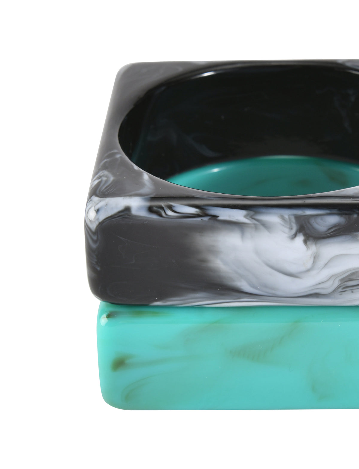 Close-up of the AUGIE BANGLE SET - EMERALD AND BLACK by TIGERMIST: two geometric bangles stacked—top in black and white marble, bottom in emerald with green marbling—on a white background.