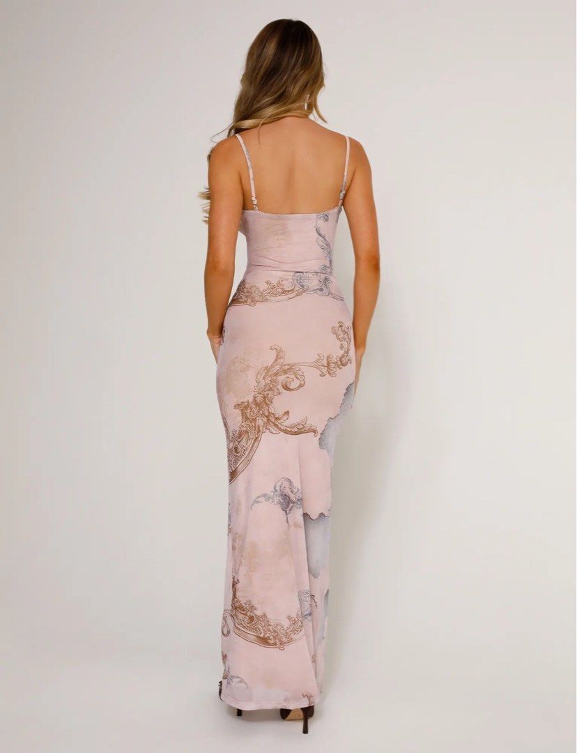 A woman with long, wavy hair models the JULIANNA DRESS - MULTI : COLLAGE : CRANES by TIGERMIST, a sleeveless maxi dress, standing against a plain light background and facing away from the camera.