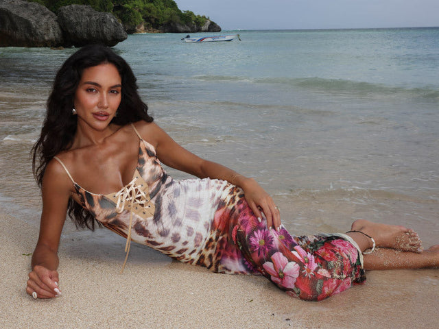 Model wearing a leopard and floral print maxi dress laying on the beach