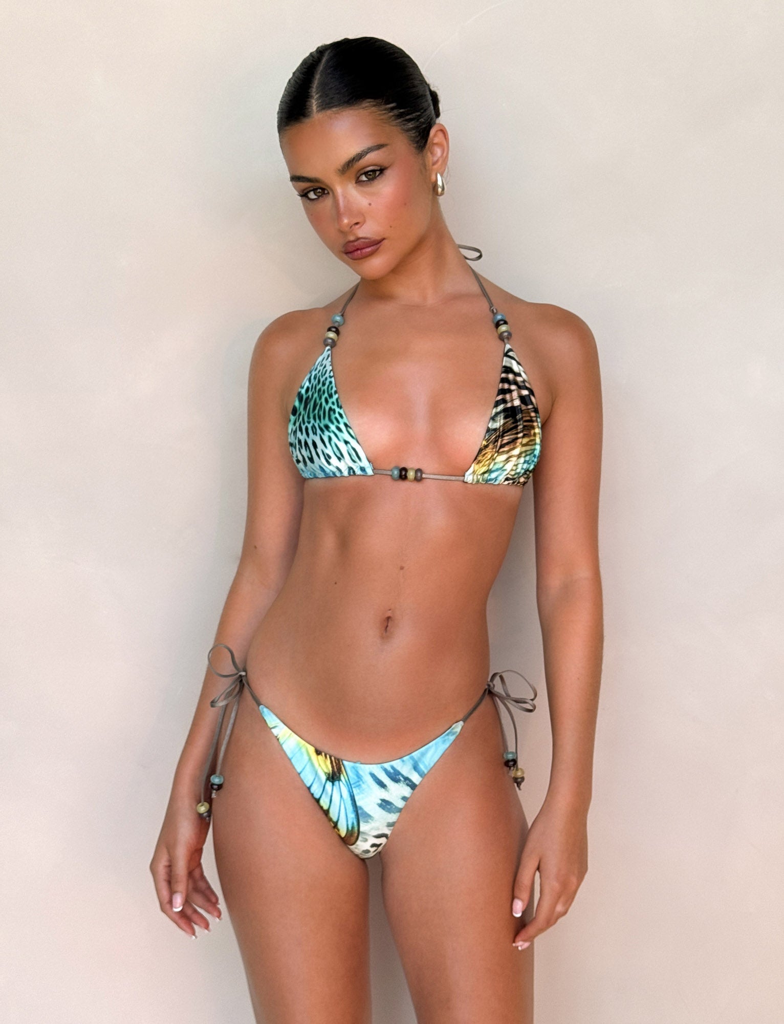 A woman with slicked-back hair and a neutral expression models the TIGERMIST FINLEA BIKINI BOTTOM in Butterfly Animal print, standing against a light background.