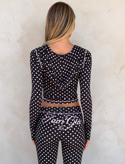 A woman wears the I.AM.GIA BLARE TRACKPANT in Black Polka Dot, a stylish black and white outfit.