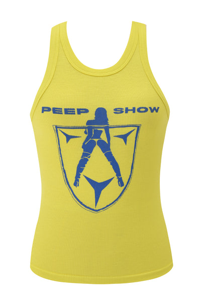 The I.AM.GIA PENELOPE TANK - BLUE PEEP SHOW is a yellow ribbed racer tank top with a blue silhouetted woman graphic, "Peep Show" text above, and a shield outline below, inspired by the iconic Penelope Tank.