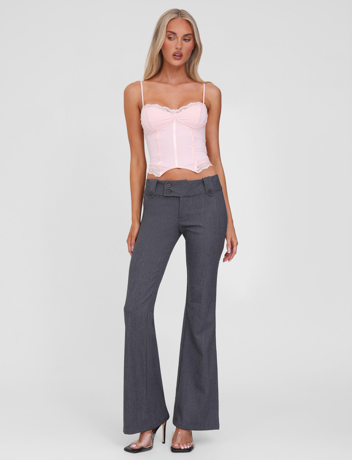 Woman with long blonde hair wears a light pink corset-style top and TIGERMIST KITTIE PANT - GREY in a flared leg silhouette, standing in high heels against a plain white background.