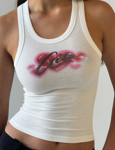 A person wears the I.AM.GIA PENELOPE TANK - PINK AIRBRUSH, a fitted ribbed racer tank with “Girl” in bold text across the chest, styled with black pants.