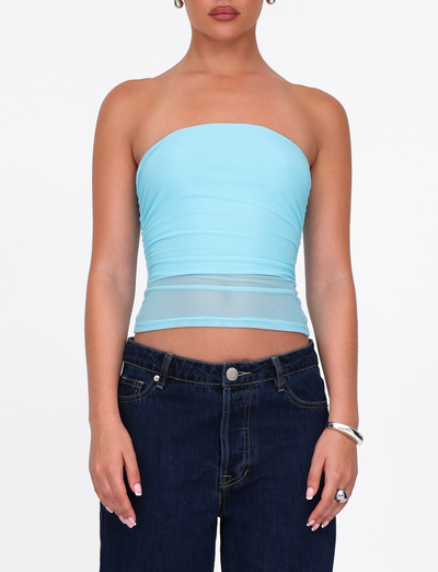 A person wears the TIGERMIST HARRIETT TUBE TOP in ICE BLUE, paired with dark blue jeans and silver accessories, standing against a plain white background.