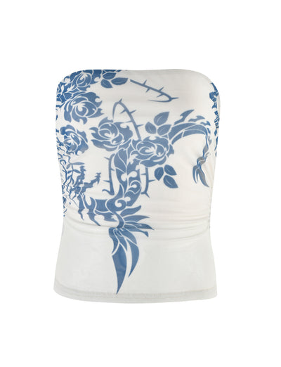 The TIGERMIST HARRIETT TUBE TOP in blue features a striking tattoo print with intricate vine and leaf patterns. This form-fitting, white strapless top showcases the vibrant design primarily on the upper section, with the print elegantly extending downward and slightly ruched sides for added texture.