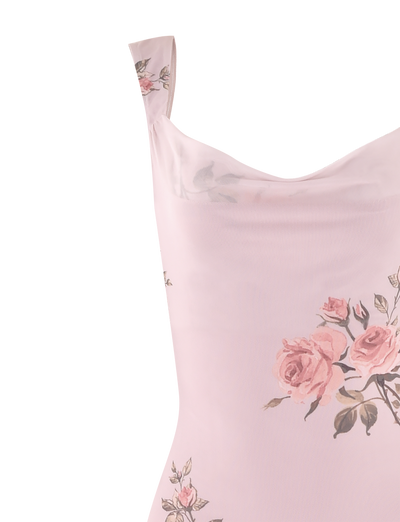 A partial view of the Morana Dress - Pink: Floral from TIGERMIST showcases a light pink dress adorned with predominantly pink roses and green leaves. The dress features thin straps and seems to be made of a soft, flowing fabric.