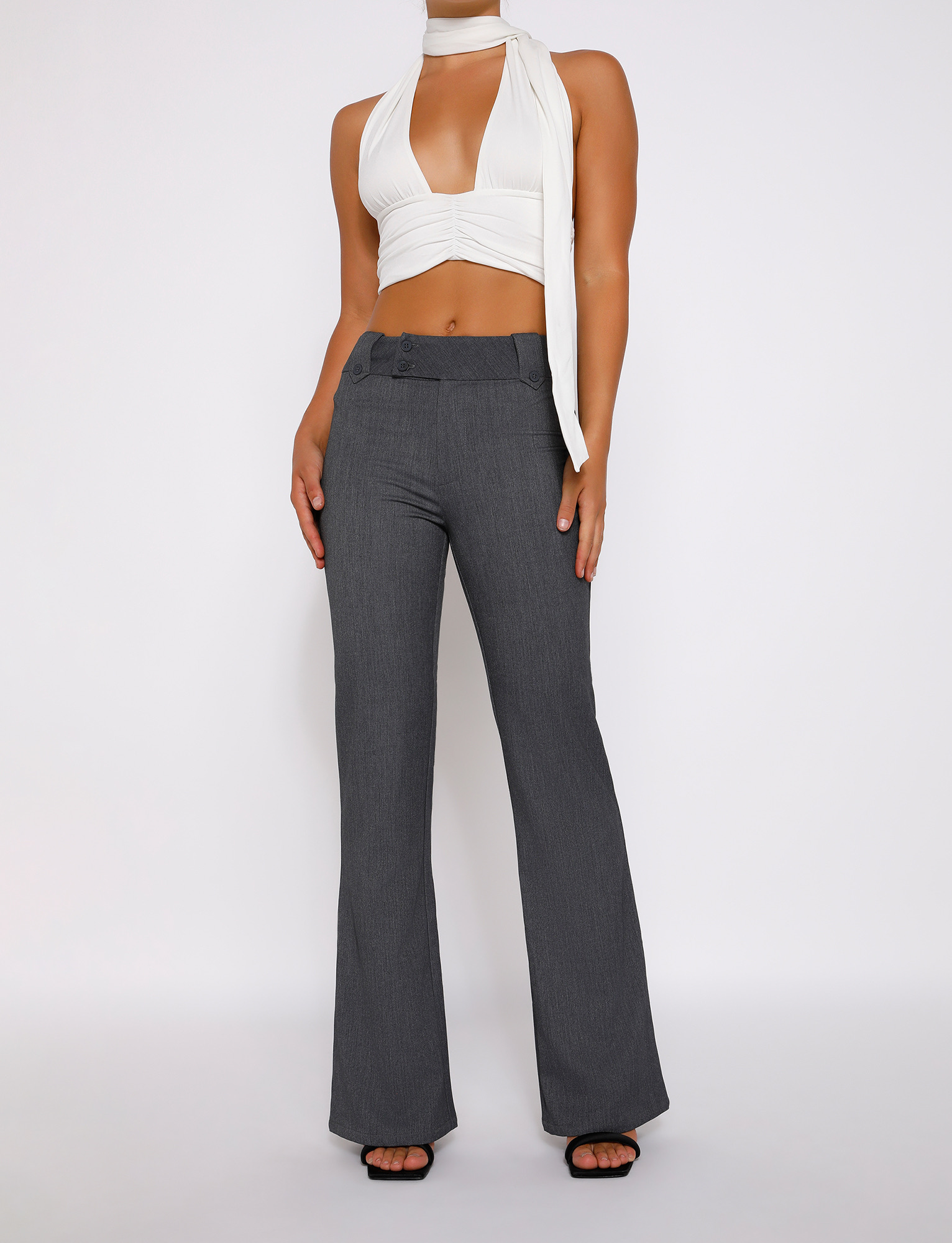 A person in a sleeveless white halter crop top and TIGERMIST KITTIE HIGH RISE PANT - GREY with a flared leg stands against a plain light background, head out of frame.