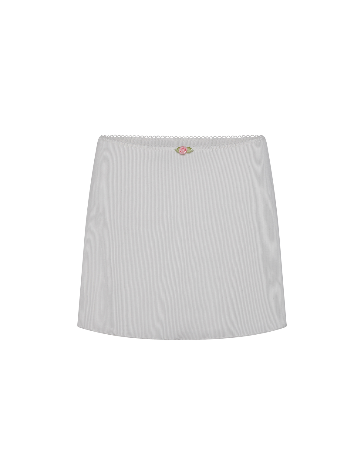 The MILANA SWIM SKIRT by TIGERMIST is a white ribbed mini skirt featuring a scalloped waistband and a small pink and green embroidered rose at the center, crafted from rib swim fabrication. Displayed on a white background.