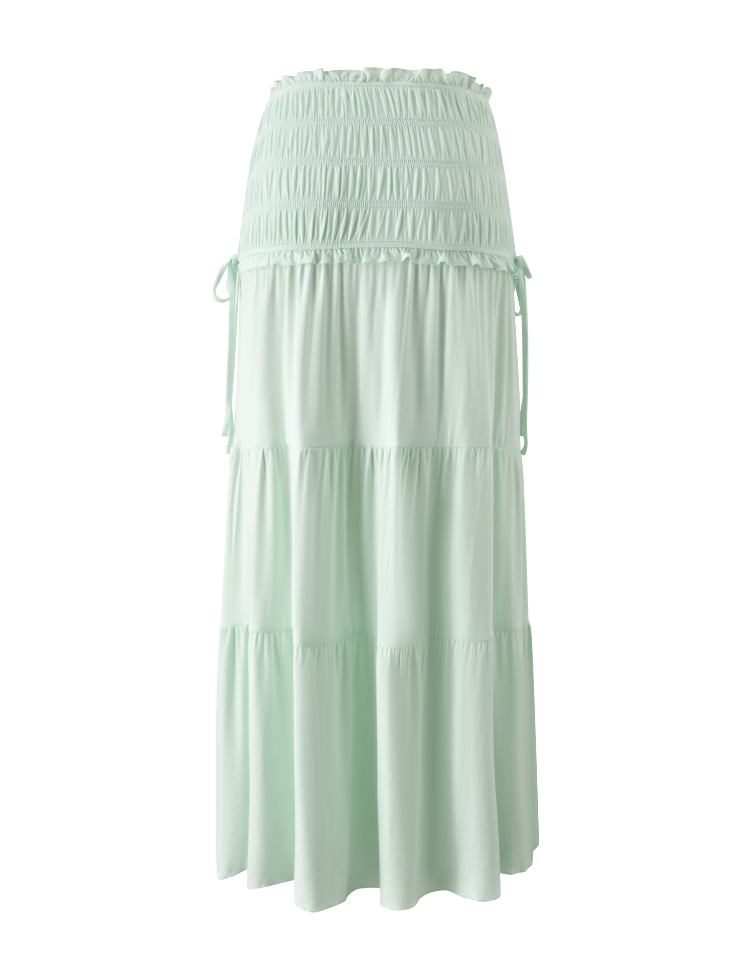 The DENALI MAXI SKIRT in Soft Mint by TIGERMIST is a light mint green maxi skirt made from soft modal fabric, with a smocked waistband, tiered design, and adjustable side ties, shown on a plain white background.