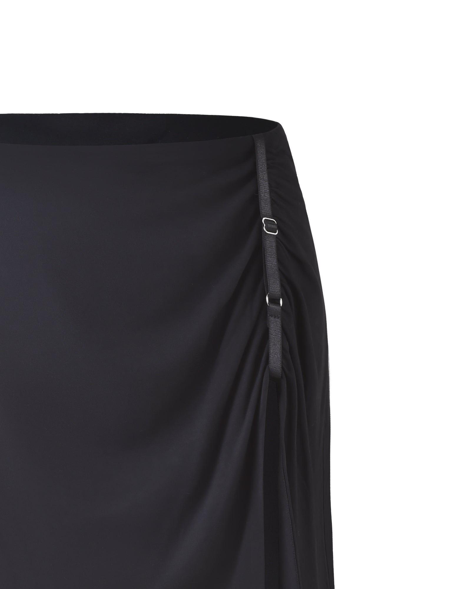 A close-up image of the ALANI SKIRT - BLACK by TIGERMIST showcases its ruched side design, adorned with adjustable black straps and silver buckles. The fabric looks smooth, while the overall style exudes a minimalist and elegant charm.