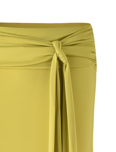 Close-up of the MIST SKIRT in Chartreuse from TIGERMIST, featuring a waistband with a twisted knot detail at the front. The knot is formed by two long, narrow strips of fabric that hang down from the waist. The material appears smooth and slightly gathered at the sides.