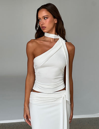 A woman with long brown hair stands against a plain background wearing an elegant white, sleeveless, asymmetrical top with a draped tie on one shoulder from TIGERMIST. She is also dressed in the matching MIST SKIRT - WHITE. With a thoughtful expression, she looks to the side.