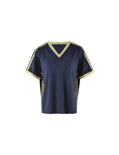 The JAYNA TEE - BLUE from TIGERMIST is a dark blue, short-sleeve sports jersey with a V-neck design. It features light yellow trim along the neckline and sleeve edges, and has light yellow stripes running down the shoulders and sides. The material appears to be mesh.
