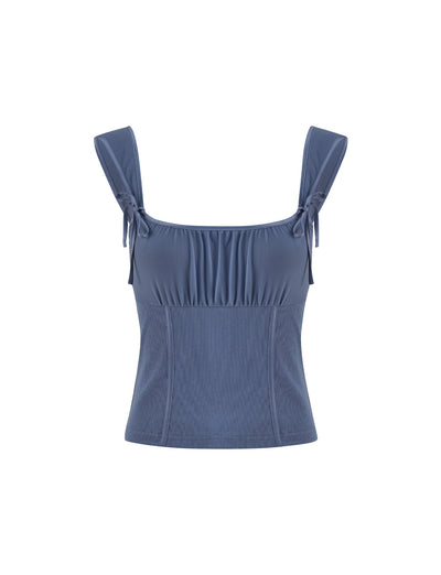 The NOEMI TOP - BLUE (Dusty Blue) from TigerMist features a stunning sleeveless design with thick shoulder straps and a ruched neckline. The fitted bodice is crafted from slightly textured fabric, accented by small tied bows on each strap near the shoulders, set against a plain white background.