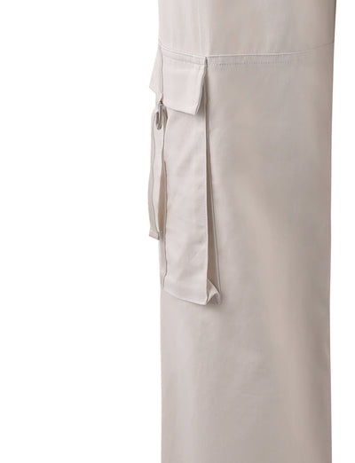 Close-up of a cream fabric cargo pocket with flap and button detail on the side of a TIGERMIST KAYA PANT - WHITE : CREAM garment. The material appears to be lightweight and slightly textured. The image focuses on the pocket, with no other visible parts of the garment or background.