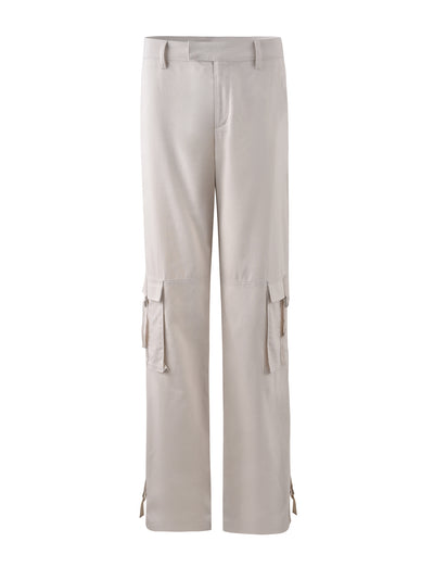 The KAYA PANT - WHITE : CREAM from TIGERMIST are a pair of cream-colored cargo pants featuring multiple side pockets and a relaxed fit. These pants come with belt loops, a button and zipper closure at the waist, and adjustable ties at the ankles. The material looks soft and comfortable.