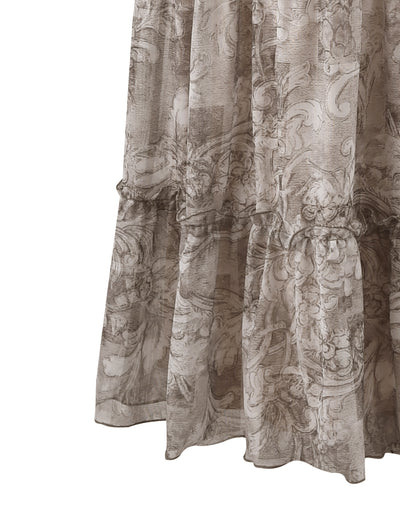 A close-up of the ALESSIA SKIRT - BROWN : FLORAL ORNATE from TIGERMIST showcases its intricate, swirling floral pattern. The flowy fabric in a light, neutral color features a delicate ruffle detail near the hem, giving the skirt a soft, romantic appearance.