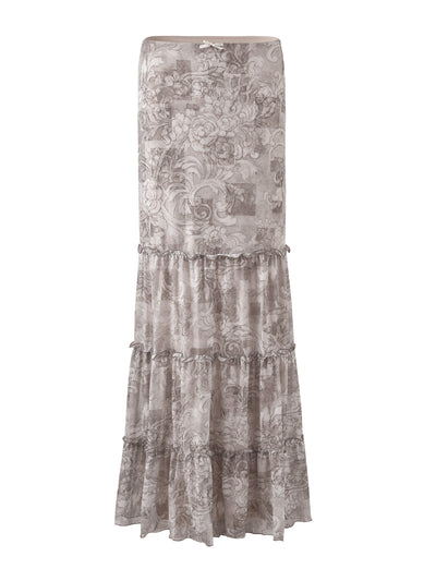 The ALESSIA SKIRT - BROWN: FLORAL ORNATE from TIGERMIST features a long, tiered design with a floral pattern in various shades of taupe and beige. It has a fitted waist and multiple ruffled layers, giving it a flowy, bohemian look.