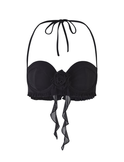 Image of the HEAVEN TOP - BLACK from TIGERMIST, featuring a black strapless design with a sweetheart neckline and a central decorative flower. The top is adorned with ruffled trim and includes a tie-up halter neck strap. Two sheer ribbon details hang from the flower.