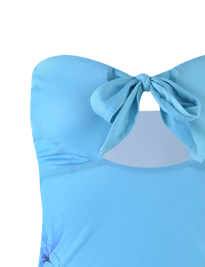 A close-up of the SOREN DRESS - BLUE : GRADIENT : GRADIENT MINT BLUE by TIGERMIST, showcasing its light blue fabric with a knotted bow at the center of the bust. The dress features a cut-out detail just beneath the bow and appears to be made from smooth and stretchy material.