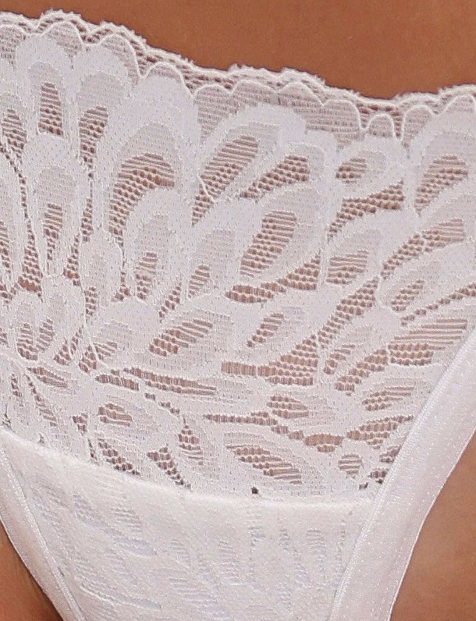 Close-up image of a section of the BROOKE SET in white by TIGERMIST, featuring intricate lace detailing with floral patterns. The sheer lace has an overlapping, scalloped edge, adding to the delicate design and includes adjustable shoulder straps for a perfect fit.