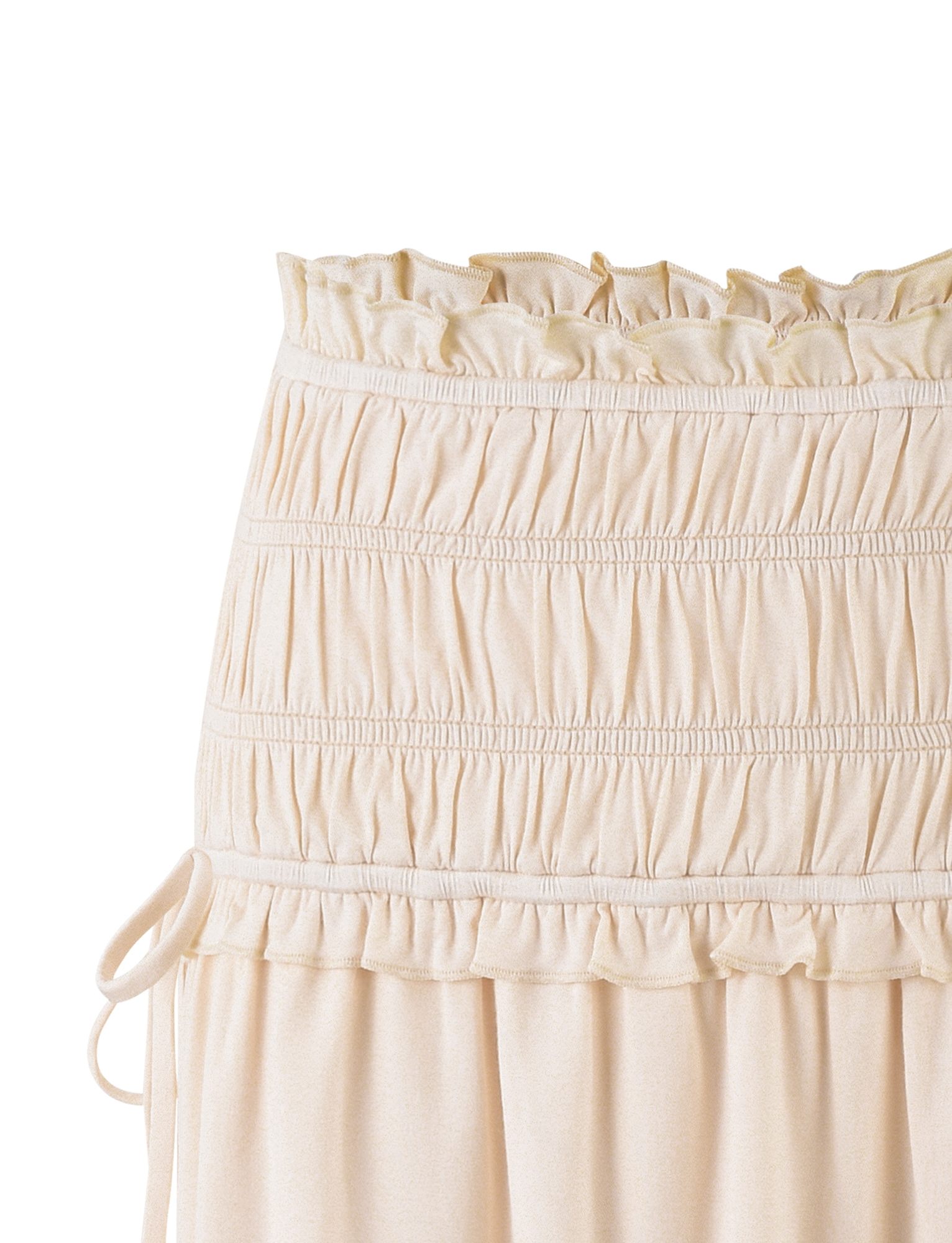 A close-up of the TIGERMIST DENALI MINI SKIRT - WHITE : BONE, showing its ruffled, elastic mid-rise waist, gathered fabric, and decorative side tie.