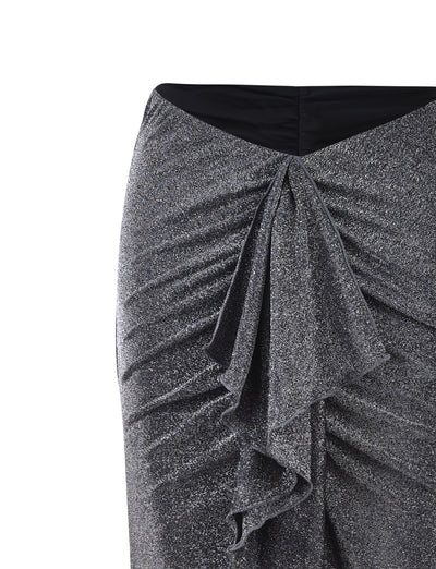 Close-up of a TIGERMIST DAISIE SKIRT - BLACK : BLACK SHIMMER with a textured, sparkly fabric. The skirt features ruching at the sides and a cascading ruffle detail down the front. The waistband is black and the garment has a fitted silhouette.