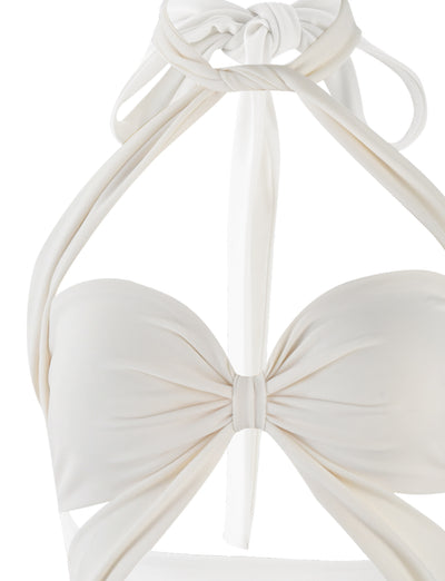 Close-up of a white Tiger Mist Tamsin Mini Dress. The dress features a twisted front design forming a bow-like shape at the center, with halter straps tied at the neck. The material appears smooth and slightly glossy.