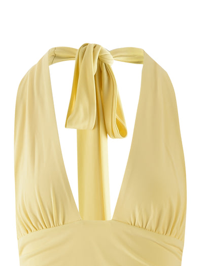A close-up of the TIGERMIST LENORA DRESS - YELLOW: PALE YELLOW: LEMON, showcasing its halter design with a deep V-neckline and ruched detailing at the bust. The halter ties are knotted at the back of the neck, creating a bow-like appearance. The fabric appears soft and slightly shiny.