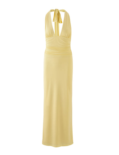 The LENORA DRESS in pale yellow from TIGERMIST is a sleeveless, floor-length gown with a deep V-neck and halter top. It features a ruched bodice and ties at the back of the neck, creating a flowing and elegant silhouette.