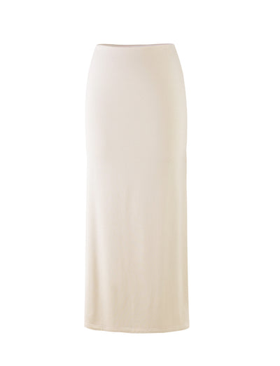 A long, fitted skirt from Tigermist, named the KAROLINA JERSEY SKIRT in off-white/ivory, is displayed on a white background. This skirt features a high waist and offers a simple, elegant design without any visible patterns, decorations, or embellishments.