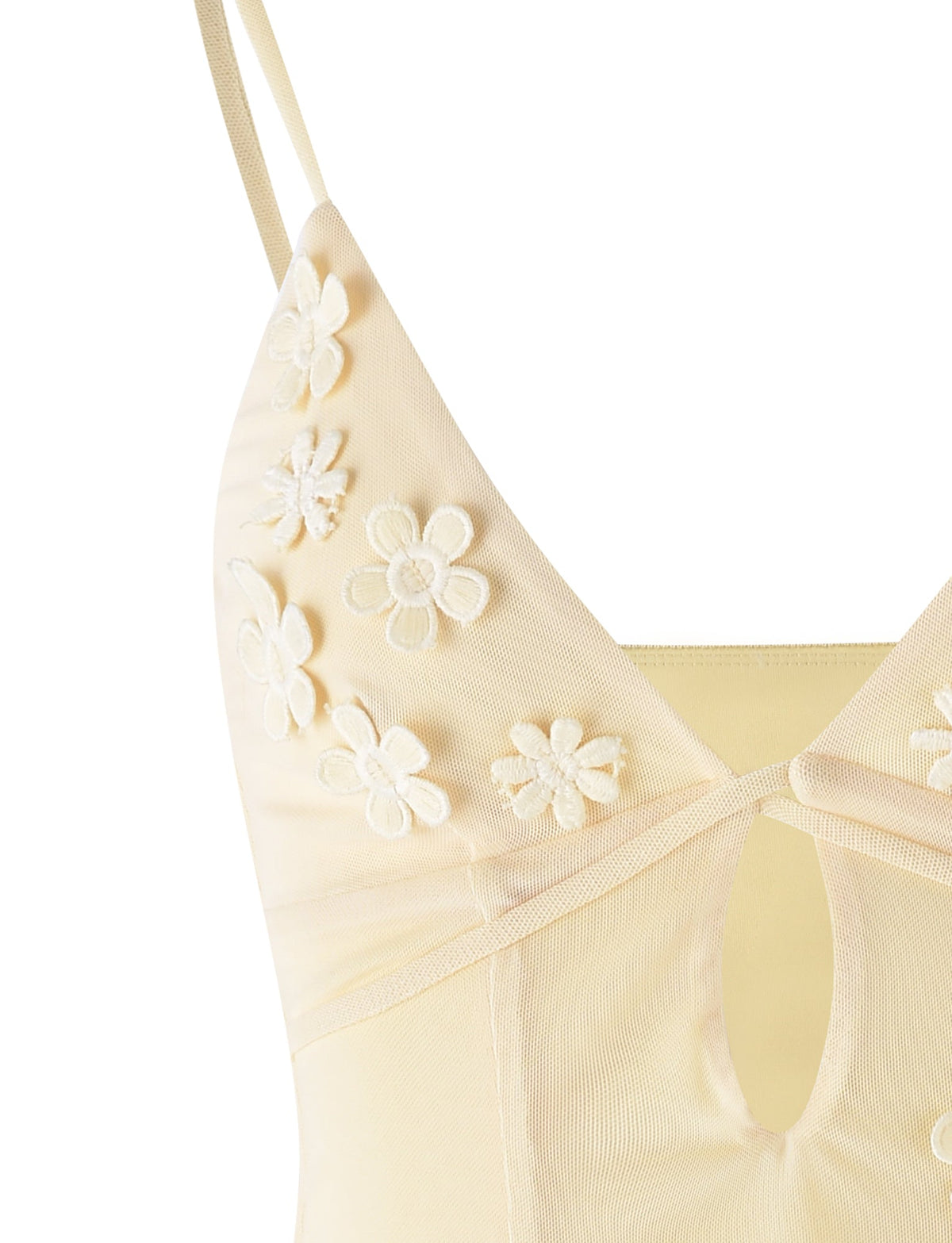 An up-close view of the TIGERMIST KATINA CAMI - YELLOW : BUTTER highlights its delicate floral embroidery. This pale yellow camisole features a V-neckline with thin shoulder straps and a small keyhole cut-out below the bust, adorned with several embroidered flowers. The fabric appears soft and semi-sheer.