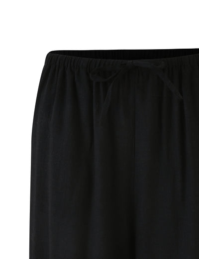 Close-up view of the waistband of a pair of black LAINEY PANT by TIGERMIST, featuring a drawstring tie in the center. The fabric appears lightweight and comfortable.