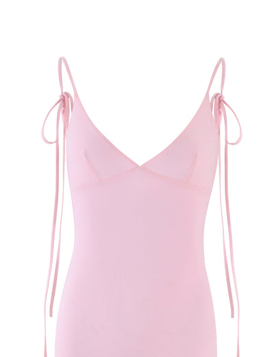 A light pink, sleeveless KYLAH DRESS - PINK: BABY PINK from TIGERMIST features thin shoulder straps that tie into bows. With a minimalist design and deep V-neckline, the fabric appears soft and delicate against the plain white background.