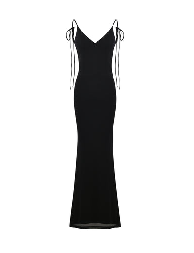 The KYLAH DRESS - BLACK from TIGERMIST is a sleek and elegant evening gown featuring a fitted bodice, flowing skirt, and spaghetti straps tied into bows at the shoulders. With its V-neckline and slightly flared hem, this dress creates a sophisticated, timeless silhouette.