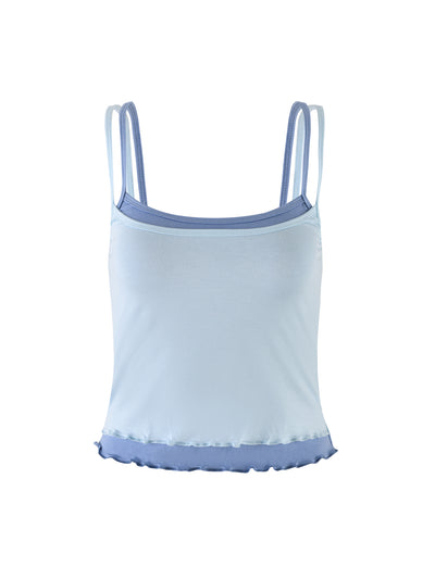 The ADAIR TOP - BLUE from TIGERMIST is a light blue spaghetti strap tank top, featuring double straps on each side. This slightly fitted design includes a light purple trim along the neckline and hemline, crafted from soft, lightweight fabric with a small ruffle detail at the bottom edge.