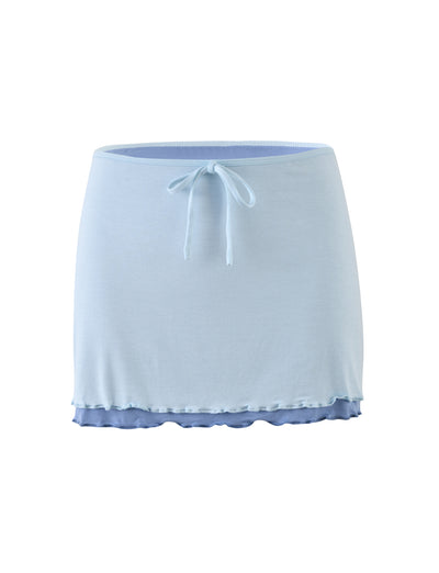 Introducing the ADAIR SKIRT - BLUE by TIGERMIST: a light blue mini skirt featuring an elastic waistband and a charming small bow tie at the front. The skirt has a double-layered hem, with the top layer in light blue and the bottom layer in a darker blue, creating an elegant ruffled effect. Crafted from soft and stretchy fabric for ultimate comfort.