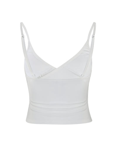 An image of the REY TOP - WHITE by TIGERMIST, a sleeveless crop top featuring adjustable spaghetti straps and a V-neck design. The top has a fitted look and is made from lightweight fabric, with a V-shaped back that offers a simple and clean style.