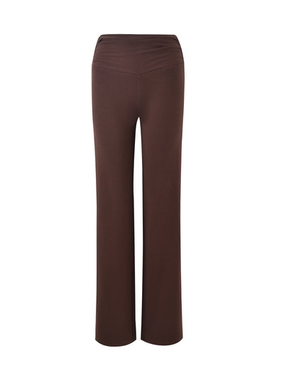 The KAVAT PANT - BROWN from TIGERMIST is displayed against a white background. These brown, high-waisted, wide-leg pants feature a ribbed texture and offer a tailored fit at the waist and hips, gently flaring out towards the bottom.