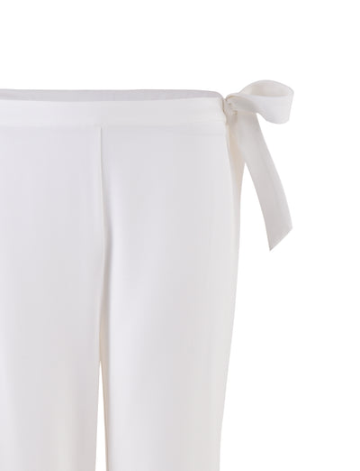 Close-up of the TRISTAN PANT - WHITE by TIGERMIST, featuring a smooth fabric and a side tie detail at the waist. The tie creates a bow on the right side for an elegant finish.