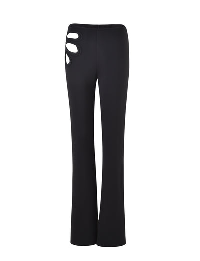 The KATO PANT - BLACK by TIGERMIST is showcased from the back, highlighting its unique cutout details on the upper right side for a stylish and modern design. The fabric appears smooth and the pants feature a straight-leg fit.