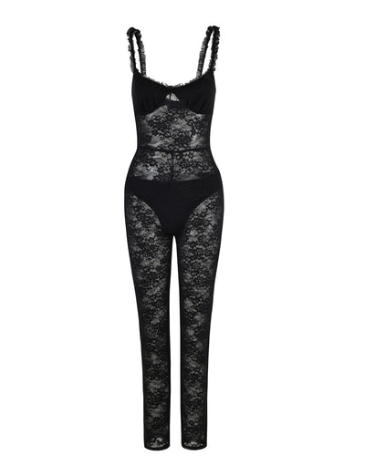 The DEJA JUMPSUIT - BLACK : LACE by TIGERMIST for women features a sleeveless design with a sheer floral lace pattern throughout, scalloped trim shoulder straps, and a cut-out detail at the bust. The jumpsuit also includes solid black panels covering the bust and hips for modesty.