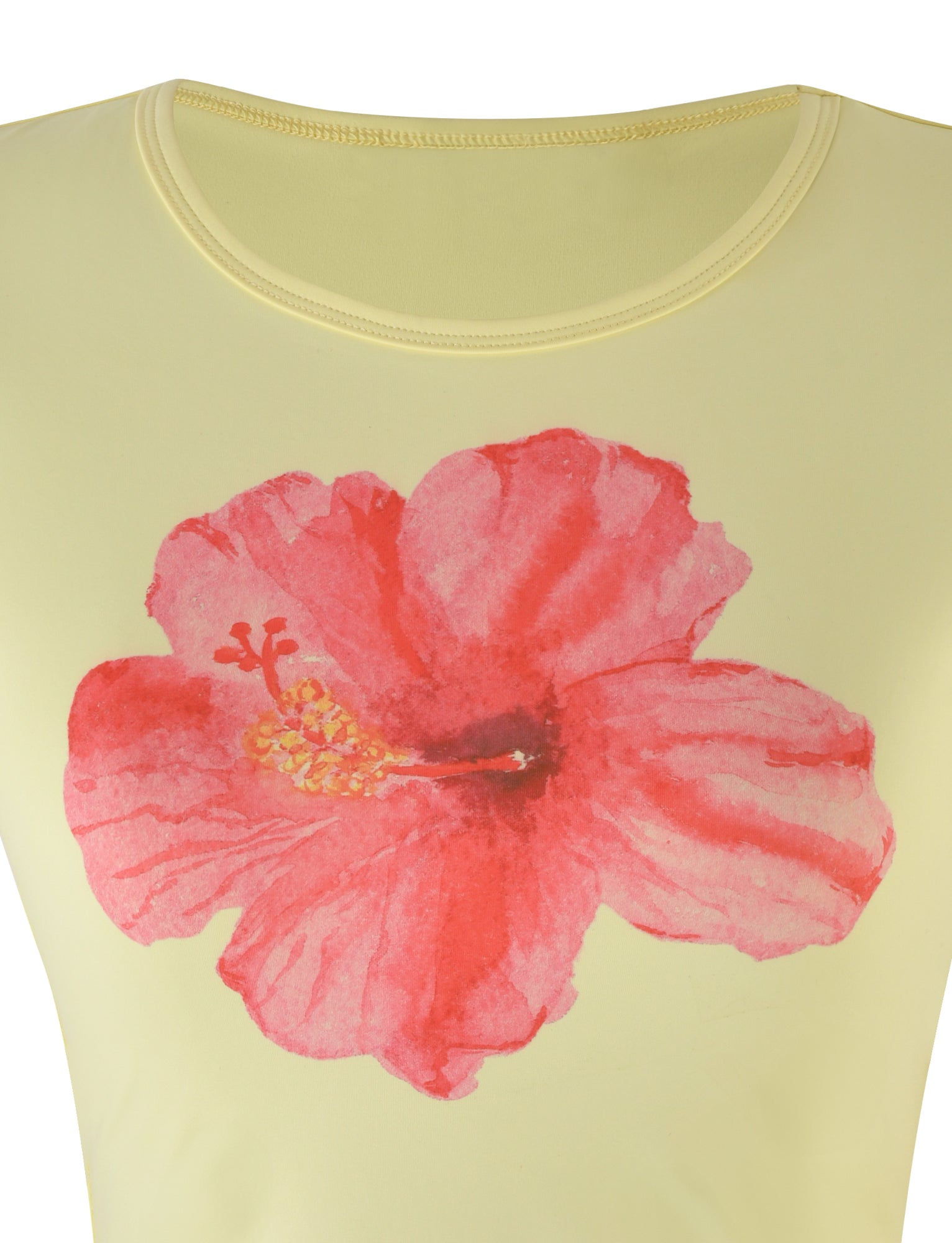 A close-up view of the JOVANA TEE - YELLOW : MACRO FLORAL : HIBISCUS from TIGERMIST showcases a light yellow fabric adorned with a large, vibrant red hibiscus flower print at its center. The detailed petals and visible pistil of the flower add a splash of color to the subtle background.