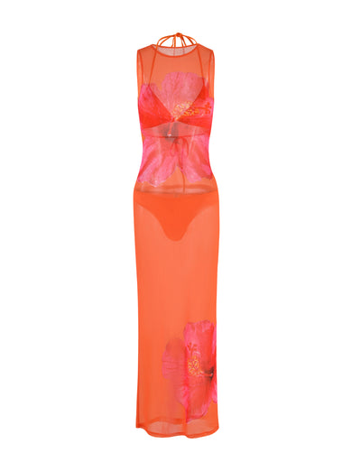 An orange dress from TIGERMIST, called the JOZIE THREE PIECE DRESS - ORANGE : MACRO FLORAL : ORANGE HIBISCUS, features a sheer, sleeveless design with large red floral prints. It includes a halter neck design with a thin strap detail at the collar, an attached undergarment, and extends to mid-calf length.