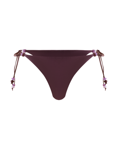 The FINLEA BIKINI BOTTOM - ZEN FLORAL by TIGERMIST features a cheeky cut in dark purple, with adjustable beaded straps embellished with small purple and pink beads, shown against a plain white background.