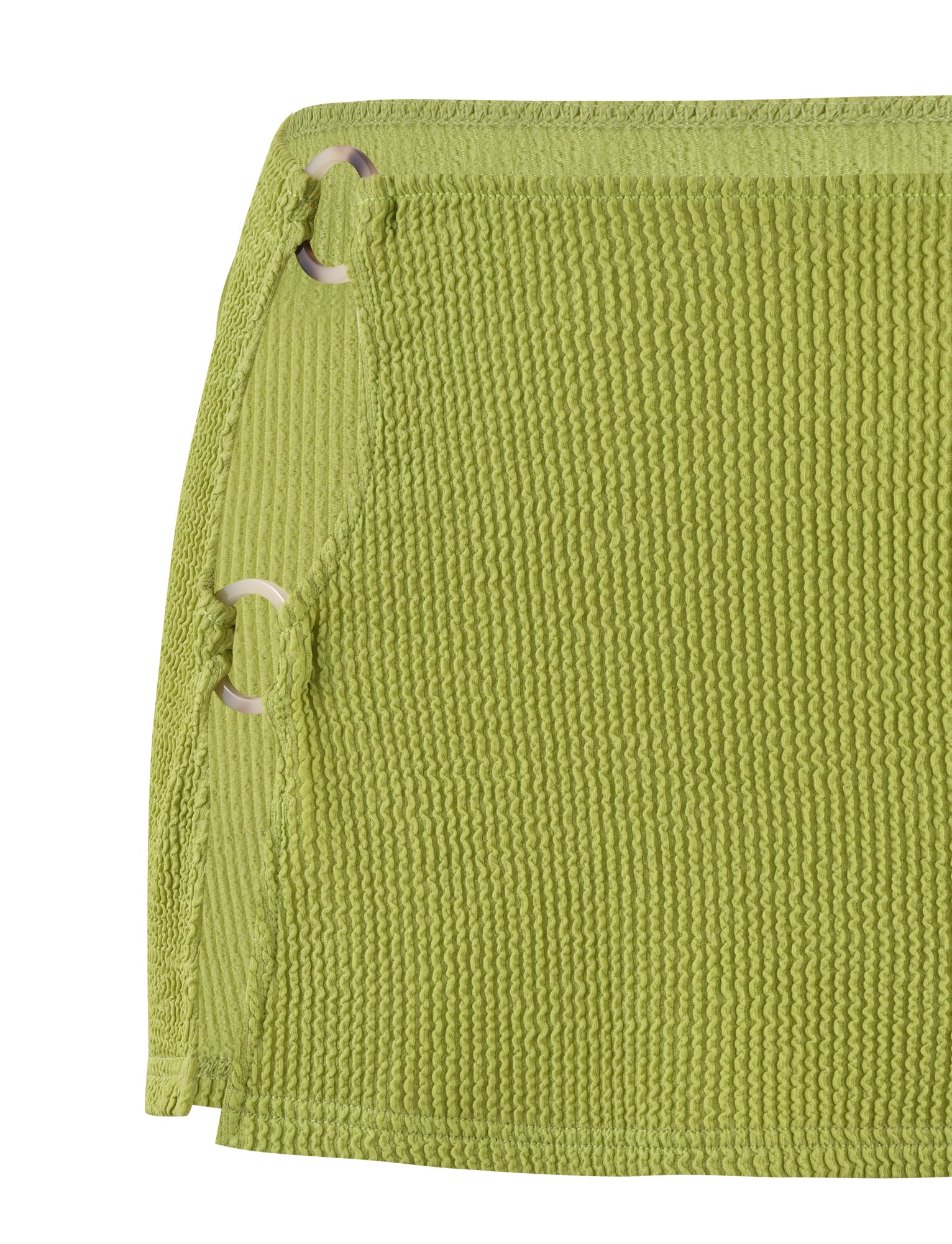 A close-up of the NEERA MINI SKIRT - GREEN by TIGERMIST showcases its lime green textured fabric with a crinkled pattern. The skirt features a partial cut-out design on the left side, held together by three white circular rings, and has a cleanly finished edge.