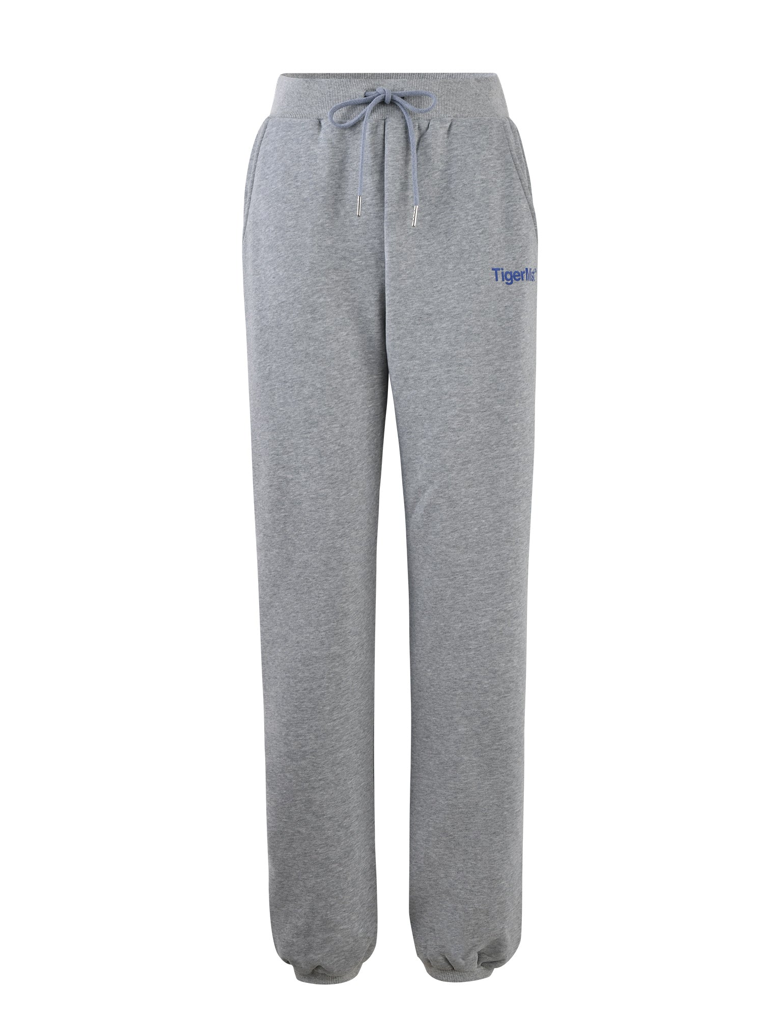 The LUMEN PANT - GREY by TIGERMIST features an elastic waistband, adjustable drawstring, and elastic cuffs at the ankles. These grey sweatpants also include side pockets and have "Tiger Mist" embroidered in blue on the upper left thigh.