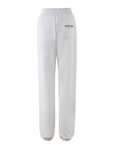 The LUMEN PANT - WHITE from TIGERMIST features a mid-rise with an elastic waistband and elastic cuffs at the ankles. Shown from the back, these pants have a small pocket on the right side near the waistband adorned with a logo and text in blue that reads "TIGERMIST" and underneath it, "Since 2007".